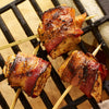 Three bacon-wrapped chicken bites are skewered and grilled, showcasing a savory appetizer.