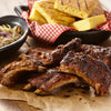 A rustic spread of tender barbecue ribs seasoned with Mccormick Grill Mates Sweet And Smoky Seasoning Rub 5.37 Oz served alongside grilled cornbread and a bowl of coleslaw.