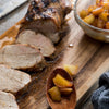 A sliced pork tenderloin is presented on a wooden board with a side of apple chutney, suggesting a delicious and balanced meal.