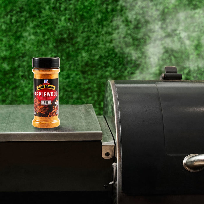 A bottle of McCormick Grill Mates Pepper &amp; Onion seasoning sits next to a grill, suggesting its use in outdoor cooking.