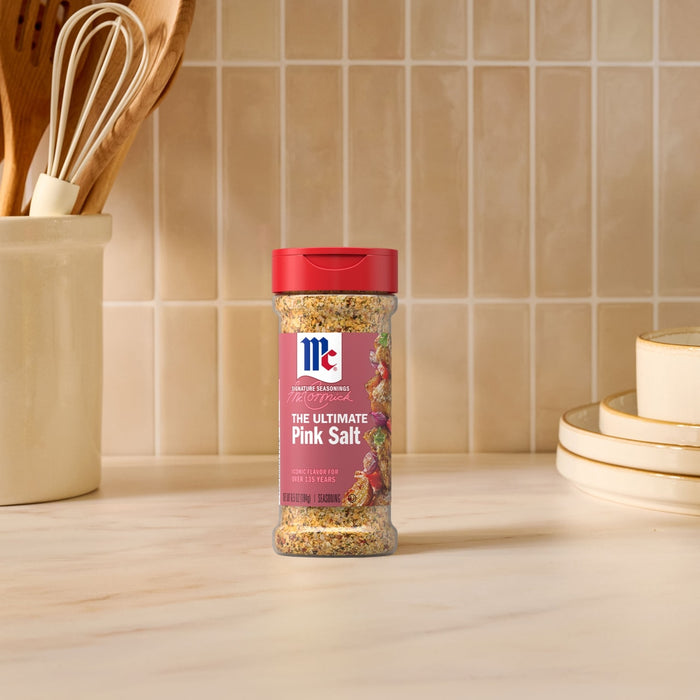 A bottle of Mccormick Himalayan Pink Salt Pepper And Garlic Seasoning Ground 6.5 Oz stands on a marble countertop in a bright kitchen setting.