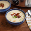 A bowl of creamy potato soup is garnished with crispy bacon bits and sliced green onions after being seasoned with Mccormick Himalayan Pink Salt Pepper And Garlic Seasoning Ground 6.5 Oz.