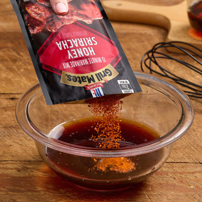 A hand pours McCormick Grill Mates Honey Sriracha seasoning into a bowl of liquid.