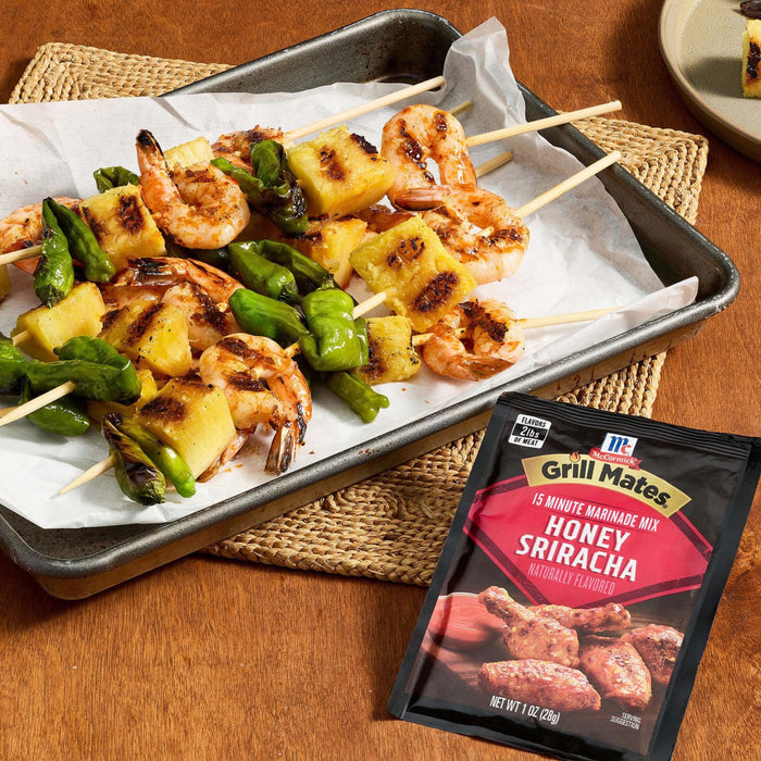 Grilled shrimp, pineapple, and asparagus skewers are displayed on a parchment-lined tray next to a McCormick Grill Mates Sweet and Smoky Rub package.