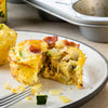 A close-up of a breakfast casserole with bacon zucchini and cheese.
