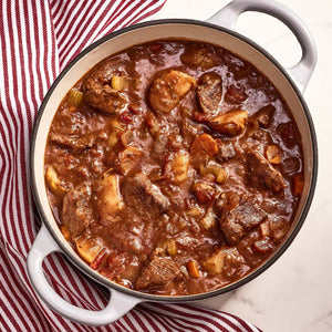 A close-up of a pot of beef stew with potatoes carrots and celery.