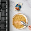 A chicken breast is being coated with McCormick Shake n Bake seasoning.