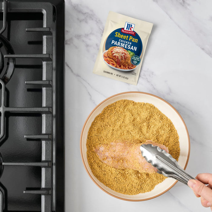 A chicken breast is being coated with McCormick Shake n Bake seasoning.