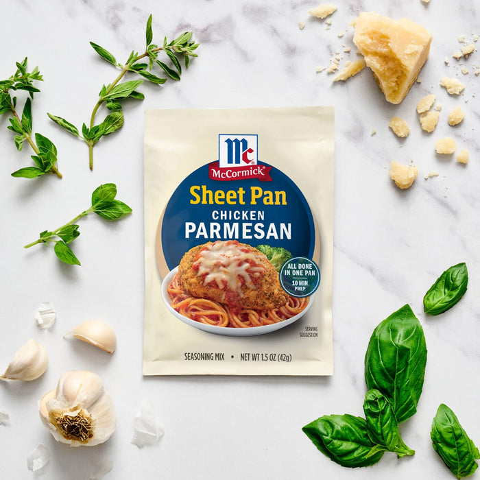 A packet of McCormick Sheet Pan Chicken Parmesan seasoning mix is displayed with fresh herbs, garlic, and parmesan cheese.