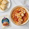 A bowl of spaghetti with sliced stuffed chicken, served with bread and McCormick Sheet Pan Parmesan seasoning packet.