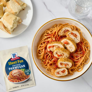A bowl of spaghetti with sliced stuffed chicken, served with bread and McCormick Sheet Pan Parmesan seasoning packet.