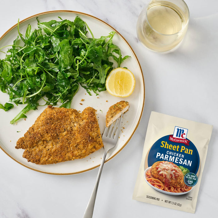 A plate with McCormick Shake n Bake Parmesan crusted chicken, a side salad, and a glass of white wine.