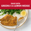 A delicious breaded fish fillet is served with fresh greens and a lemon wedge.