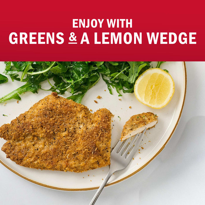 A delicious breaded fish fillet is served with fresh greens and a lemon wedge.