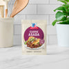 A packet of McCormick Carne Asada seasoning mix is displayed on a countertop.