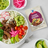 A bowl of carne asada with toppings next to a packet of McCormick Carne Asada seasoning.