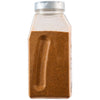 A side view of a large, clear plastic container of Mccormick Culinary Peruvian Seasoning Powder 24 Oz, showing the brownish-orange spice blend inside.