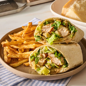 A plate featuring a sliced chicken caesar wrap and a side of crispy french fries seasoned with Mccormick Perfect Pinch Rotisserie Chicken Seasoning Powder 5 Oz.