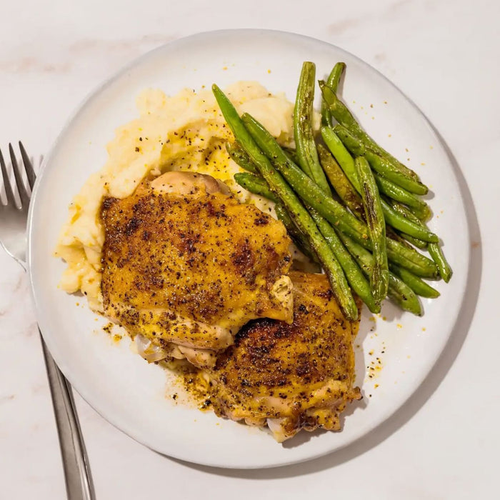 A plate of roasted chicken thighs and green beans served over mashed potatoes is seasoned with Mccormick Signature Seasoning Lemon Pepper Oz.
