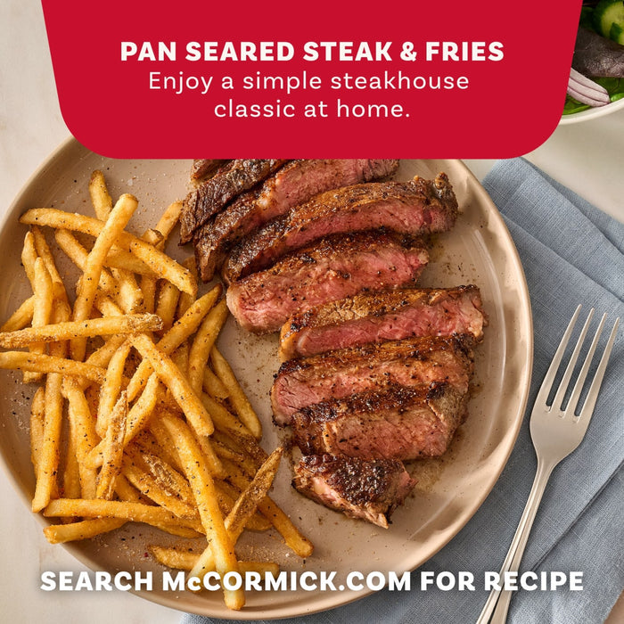 A plate of pan seared steak and fries seasoned with Mccormick Perfect Pinch Steak Seasoning Ground 7 Oz alongside a fresh salad and a fork.