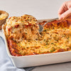 A skillet of penne pasta with chicken, spinach, and tomatoes, topped with grated cheese.