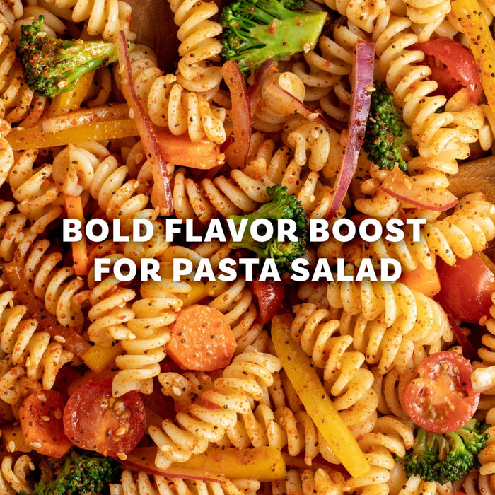 A close up view of rotini pasta salad tossed with fresh broccoli florets, sliced carrots, red onions, and cherry tomatoes seasoned with Mccormick Signature Seasoning Salad Supreme Oz for a bold flavor boost.