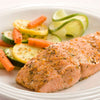 A perfectly seared salmon fillet seasoned with Mccormick Garlic And Herb Seasoning Ground 4.37 Oz served alongside a colorful medley of sautéed zucchini and carrots.