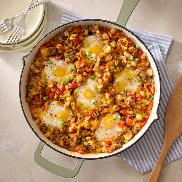A hearty breakfast skillet filled with potatoes, sausage, and peppers is topped with six fried eggs and seasoned with Mccormick Roasted Garlic And Red Bell Pepper Seasoning Ground 4.34 Oz.