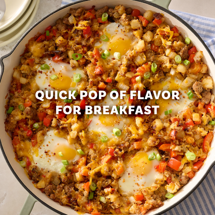 A hearty breakfast skillet filled with sausage, potatoes, and peppers is seasoned with Mccormick Roasted Garlic And Red Bell Pepper Seasoning Ground 4.34 Oz and topped with several fried eggs.