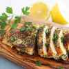 A sliced chicken breast rests on a wooden board seasoned with Mccormick Onion And Herb Seasoning Crystal 4.16 Oz and garnished with fresh parsley and lemon.