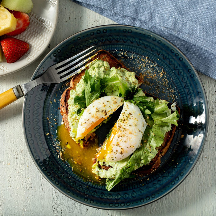 A delicious breakfast of avocado toast topped with greens and a poached egg is enhanced with a sprinkle of Mccormick Onion And Herb Seasoning Crystal 4.16 Oz.