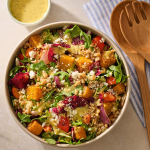 A vibrant grain bowl featuring roasted squash and fresh greens is perfectly seasoned with Mccormick Vegetable Seasoning Assorted Form 4.16 Oz and drizzled with a creamy dressing.