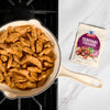 A pan of cooked teriyaki chicken strips sits next to a packet of McCormick Teriyaki Glaze.