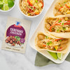 A packet of McCormick Teriyaki Chicken seasoning is displayed next to a plate of teriyaki chicken tacos with a side of rice.