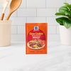A packet of McCormick Slow Cookers Brown Gravy Roast seasoning mix sits on a kitchen counter.
