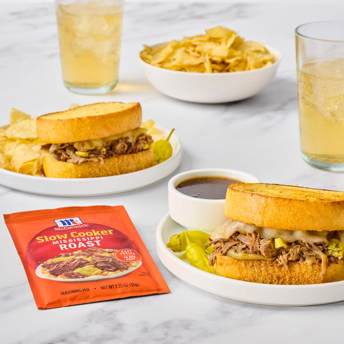 A delicious meal featuring McCormick Slow Cookers French Dip Sauce Mix, served as a sandwich with chips and drinks.