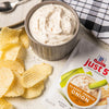 ['McCormick Just 5 Classic French Onion Dip &amp; Seasoning Mix with potato chips and a bowl of dip.']