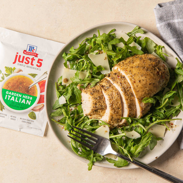 ['A plate of arugula salad with sliced chicken breast topped with McCormick Just 5 Garden Herb Italian Dressing &amp; Seasoning Mix.']