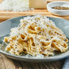 ['A plate of pasta with a creamy sauce and grated cheese.']