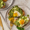 ['Two slices of toasted bread topped with pesto and a fried egg.']
