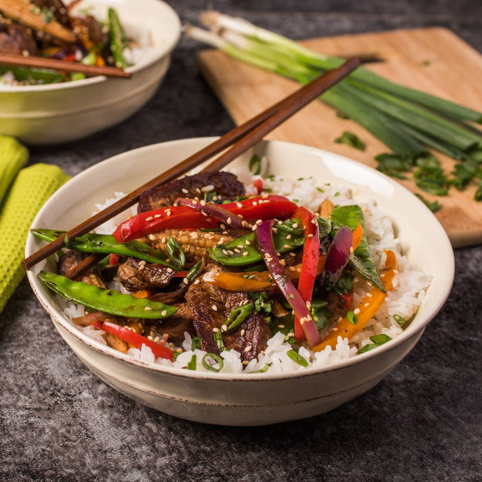 ['A bowl of rice with stir-fried vegetables and meat.']