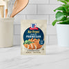 A packet of McCormick Air Fryer Garlic Parmesan seasoning mix is displayed on a countertop.