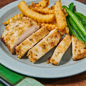 A plate with sliced seasoned chicken breast, crinkle-cut fries, and green beans.