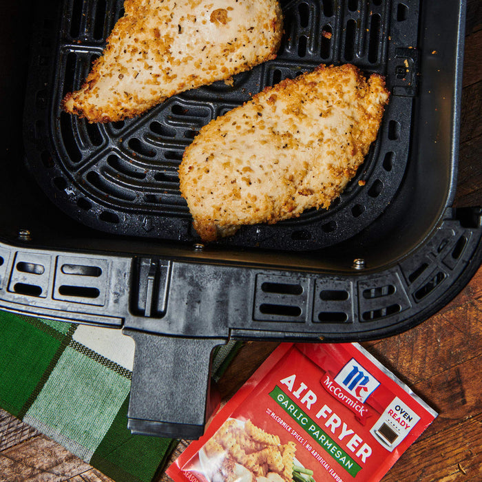['Two breaded chicken breasts are cooked in an air fryer with McCormick Garlic Parmesan seasoning.']