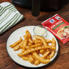 ['McCormick Air Fryer Garlic Parmesan seasoning mix with a plate of seasoned fries and a small bowl of dipping sauce.']