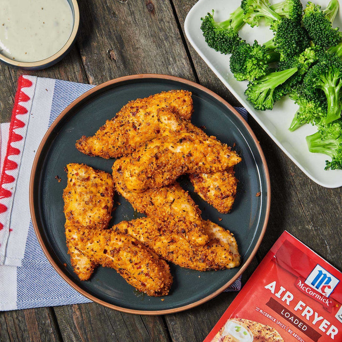 ['McCormick Air Fryer Loaded seasoning packet with a plate of breaded chicken tenders and a side of broccoli.']