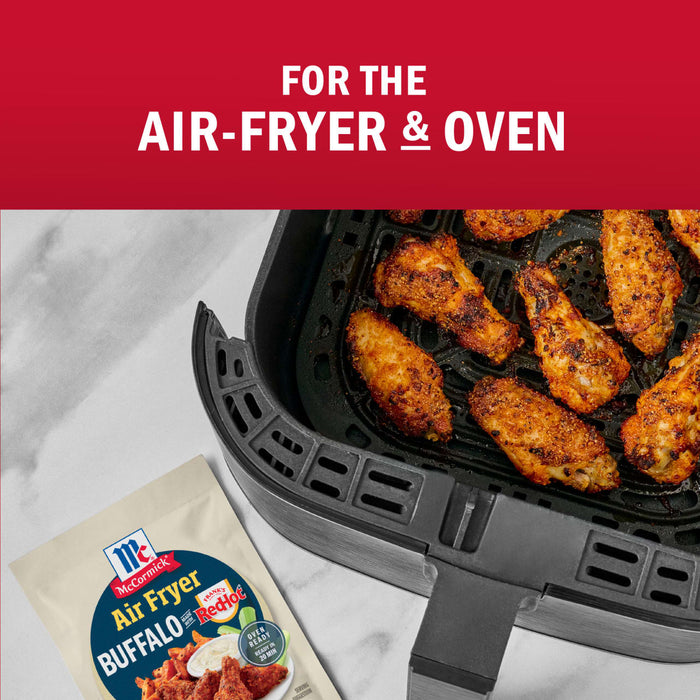 McCormick Air Fryer Buffalo Wings seasoning mix is shown with cooked chicken wings in an air fryer, highlighting its suitability for both air fryers and ovens.