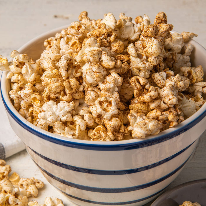 ['A bowl of popcorn with a blue and white stripe pattern.']