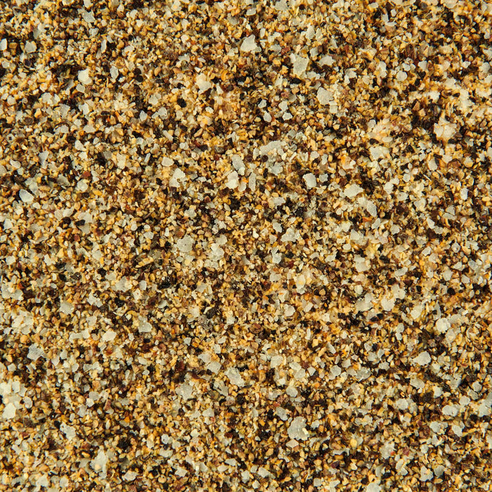 A close-up, top-down view of a granular seasoning blend, featuring white salt crystals, black pepper, and various brown and tan spices, representing Mccormick Grill Mates Classic Seasoning Assorted Form 2.85 Oz.