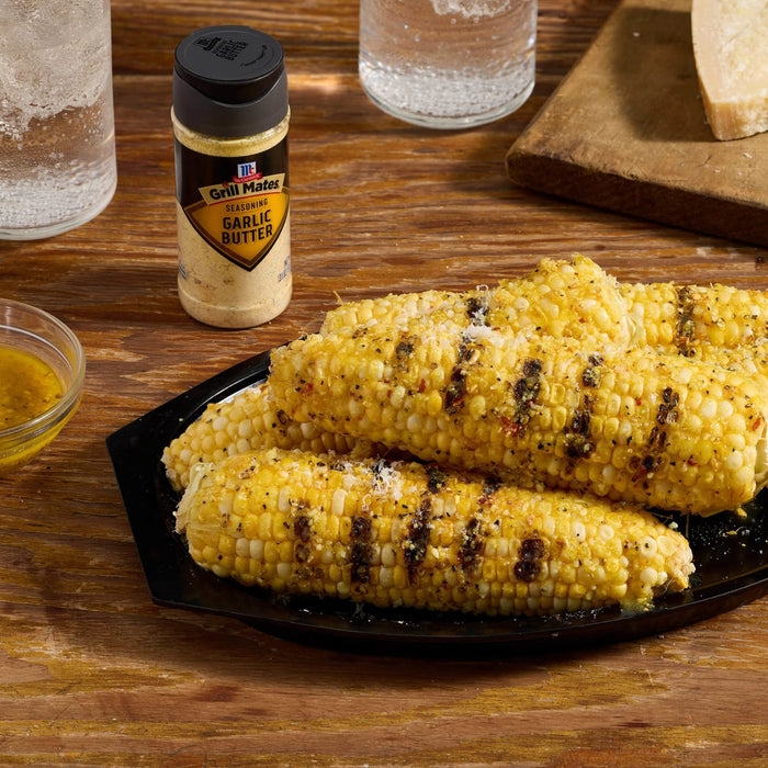 Grilled corn on a black plate with a bottle of McCormick Culinary Roasted Garlic &amp; Herb Seasoning.